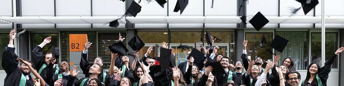 Gruppenbild von Absolventen, die ihren Akademikerhut in die Luft werfen 